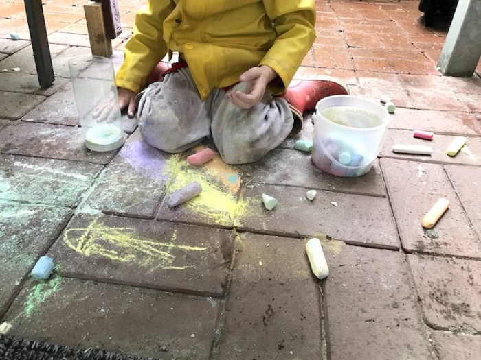 Sohn 2.0 sitzt im Regen und malt mit Kreide. | Mehr Infos auf Mamaskind.de
