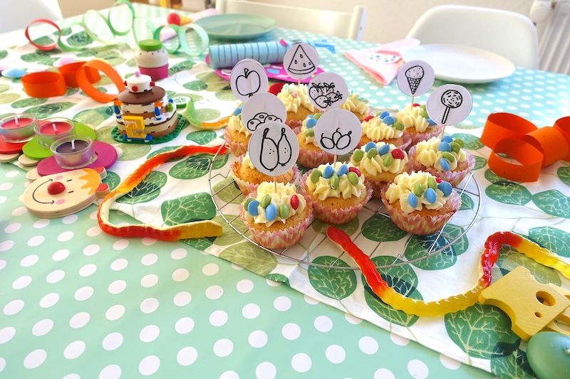 Raupe Nimmersatt Cupcakes mit Gummischlange, Holz-Essen und gebastelter Papierdeko | Mehr coole Ideen zum Raupe Nimmersatt Mottogeburtstag auf Mamaskind.de